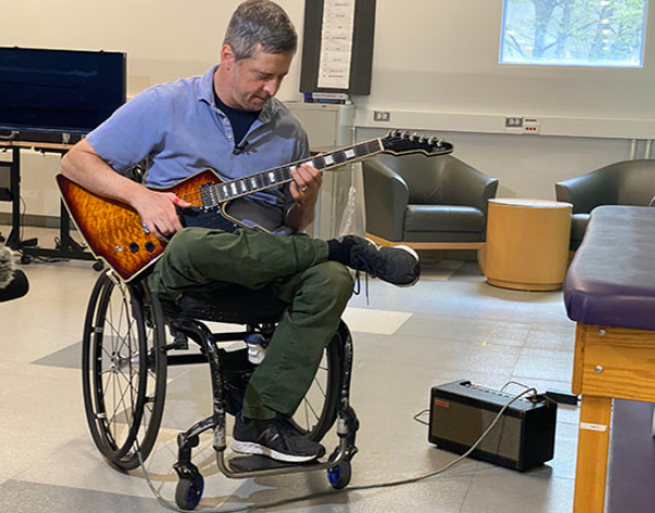 Man in wheelchair playing Gibson electric guitar